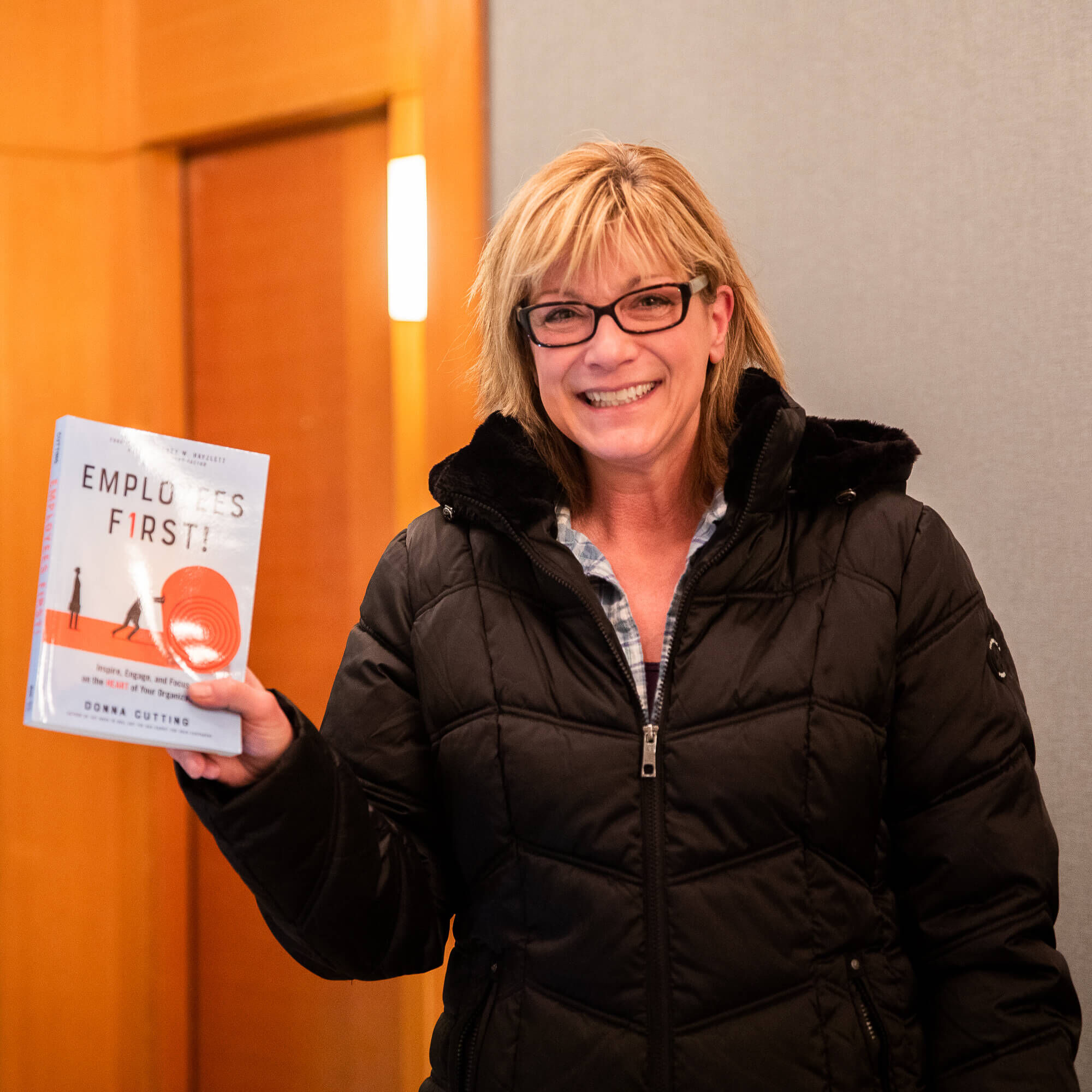 Taylor Kumlue, owner of Noodle-Ly, smiles while holding a copy of the Employees First book at a customer service training